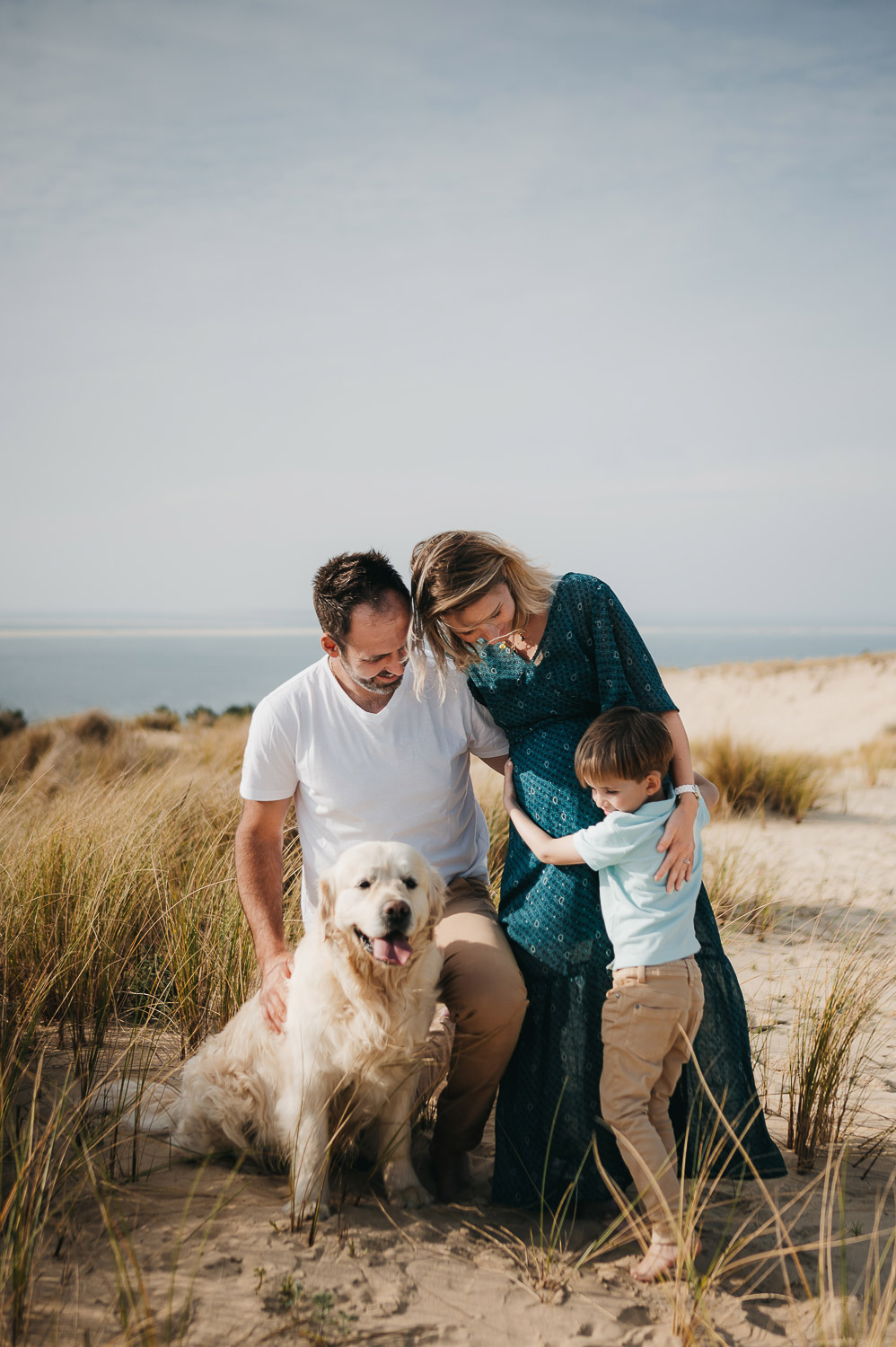 une photos de famille au bord de mer, avec leur chien.
