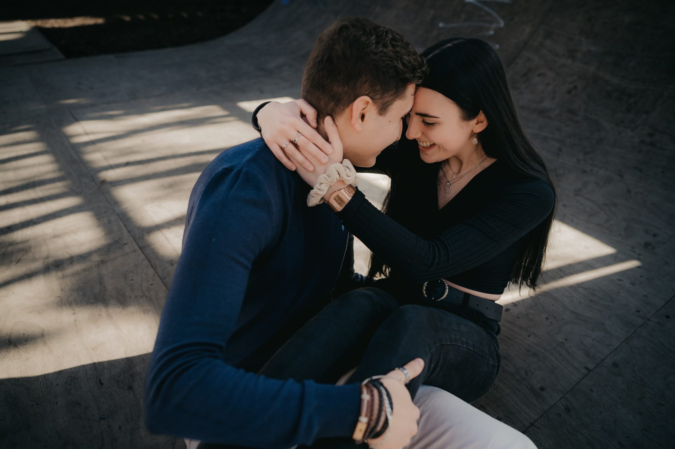 un jeune couple assis par terre, se tenant dans les bras avec tendresse le temps d'une séance photo couple à Bordeaux