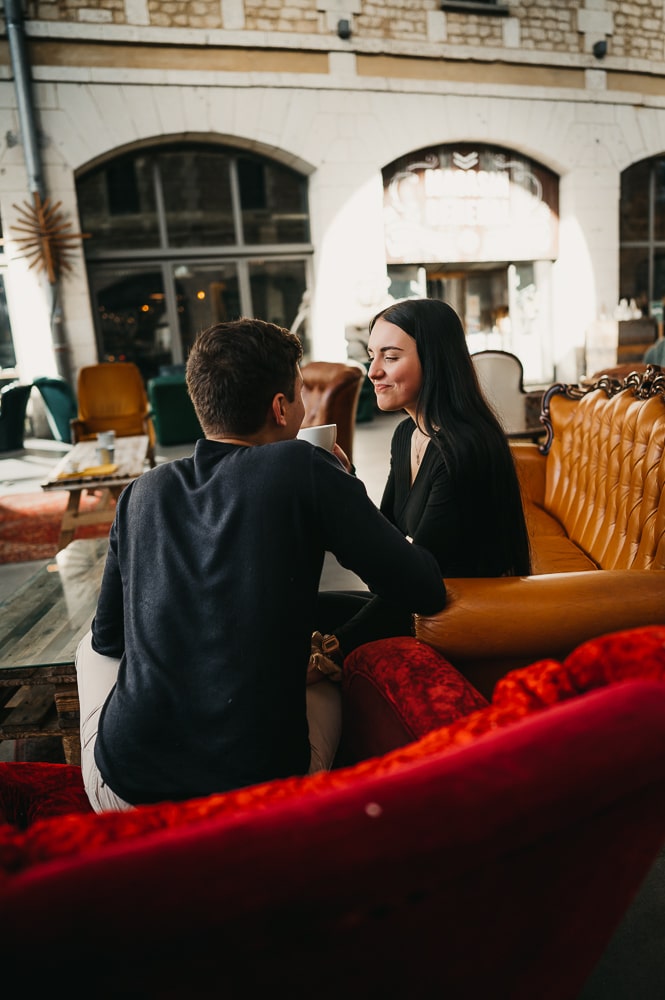 une jeune femme qui tient une tasse de café assis sur un canapé lors d'une séance photos couple à Bordeaux