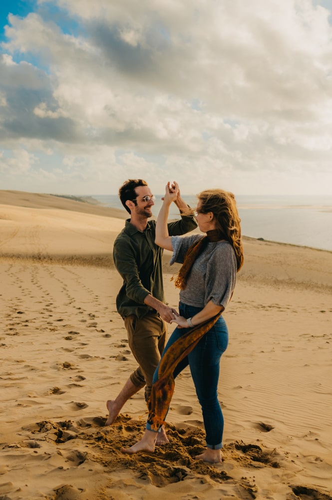 Une photographe couple à Arcachon qui fige un jeune couple qui danse sur le sable face à la mer