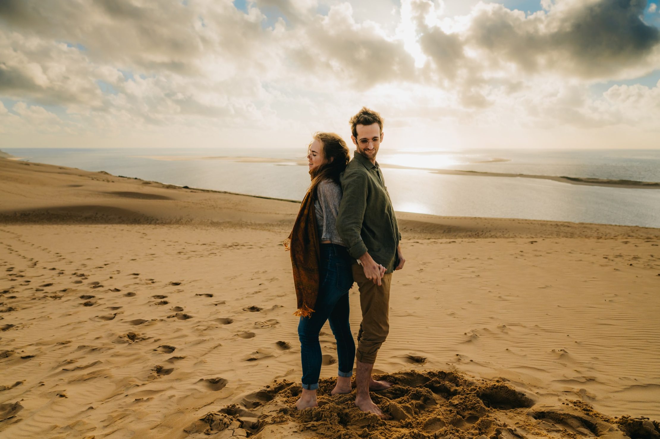 un homme et une femme, sur le sable dos à dos en haut de la dune du pyla