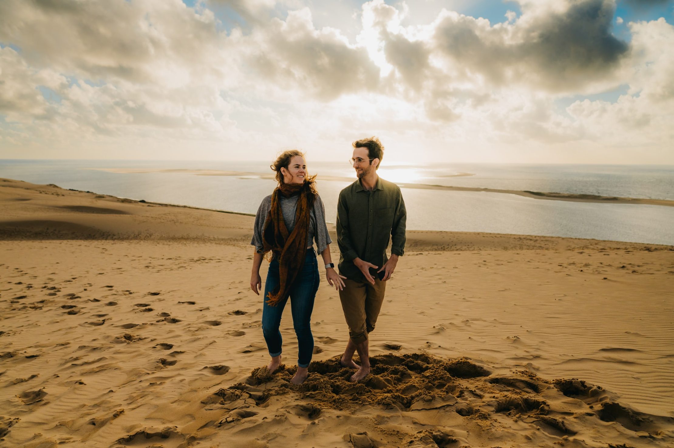 un jeune couple d'amoureux qui était dos à dos au départ, se retourne l'un vers l'autre sur le sable de la dune du pyla