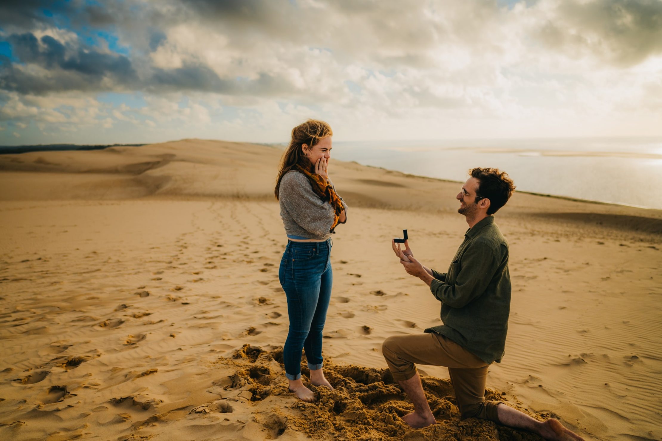 une jeune fille très étonné par la magnifique demande en mariage de son petit ami, lors d'une balade en amoureux sur le sable à la dune du pyla