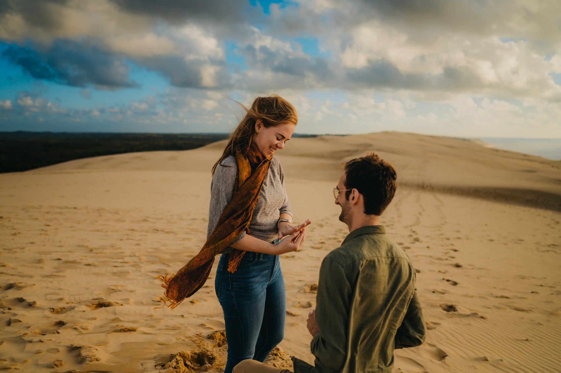 une jeune femme regarde la jolie bague de fiançailles que sont petit ami vient de lui offrir il y a quelques secondes lors d'une promenade romantique en haut de la dune du pyla