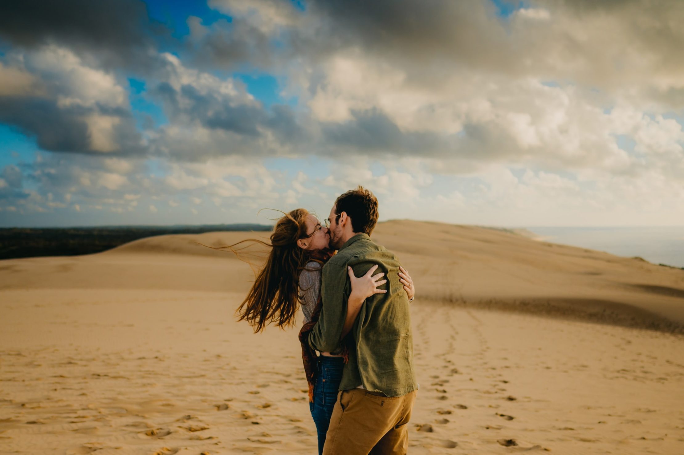 un jeune couple qui s'embrasse avec tendresse lors d'une balade à la dune du pilat