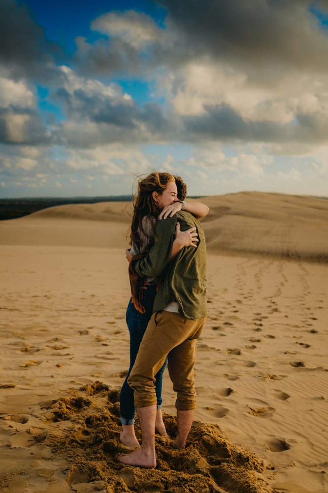 une jeune femme fait un câlin à son amoureux en haut de la dune du pilat