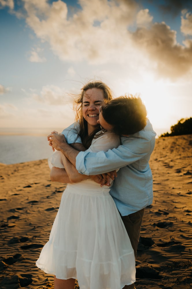 Séance photos couple à Arcachon, deux amoureux qui se serrent dans les bras en haut de la dune du pilat