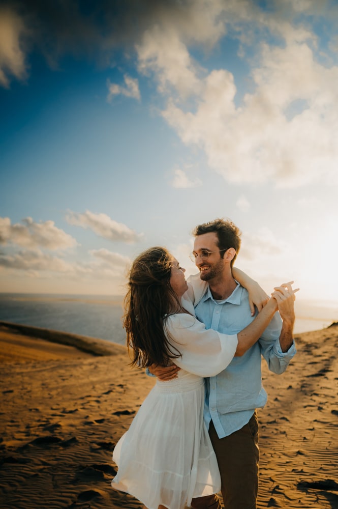 Une photographe couple à Arcachon qui fige un un couple d'amoureux qui dansent lors d'une séance photos, à Arcachon, sur la dune du pilat