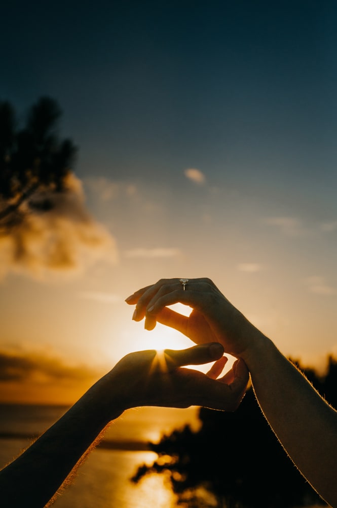Deux mains qui se touchent à la dune du pilat, lors d'une séance photos couple avec un couché de soleil en arrière plan