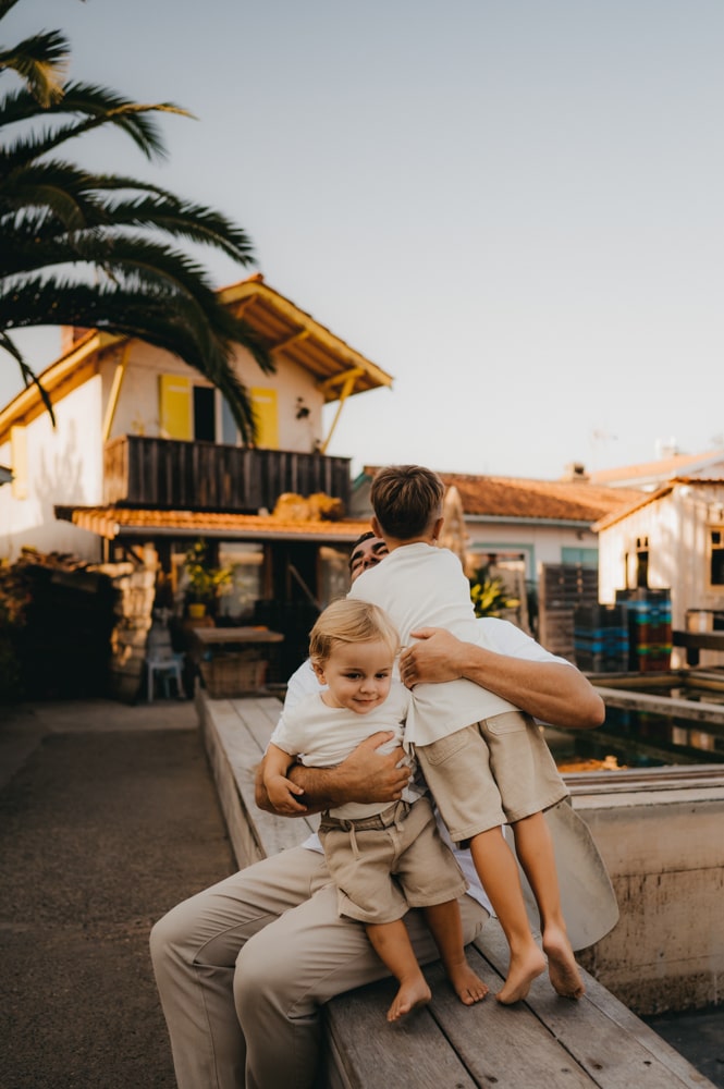 Papa posant un bisou sur le front de ses enfants au Cap-Ferret