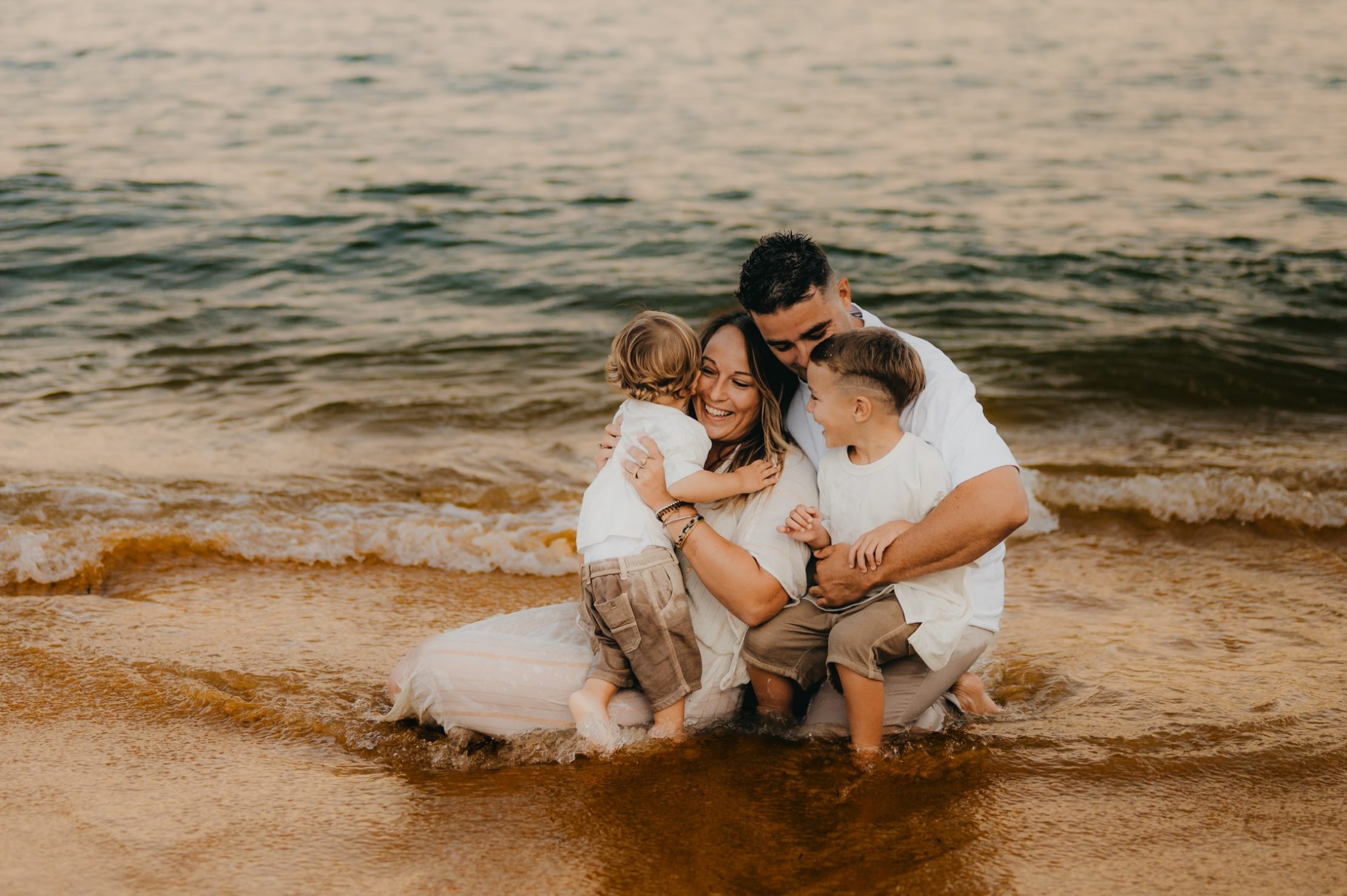 Mallory, Jean-Baptiste et les enfants échangeant un câlin sur le sable