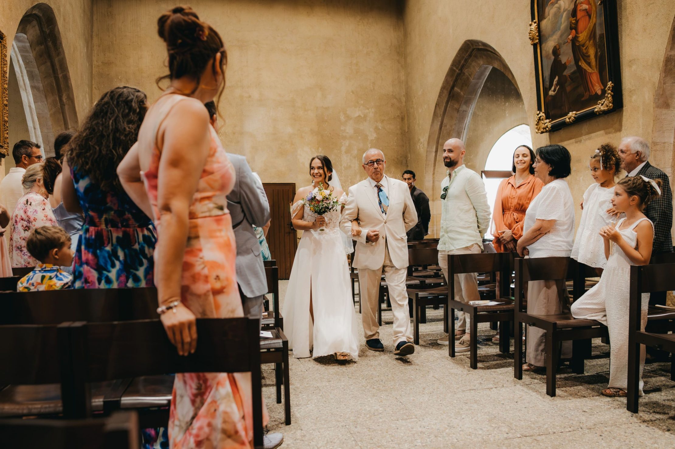 la mariée au bras de son papa qui marche dans l'allée principale de l'église