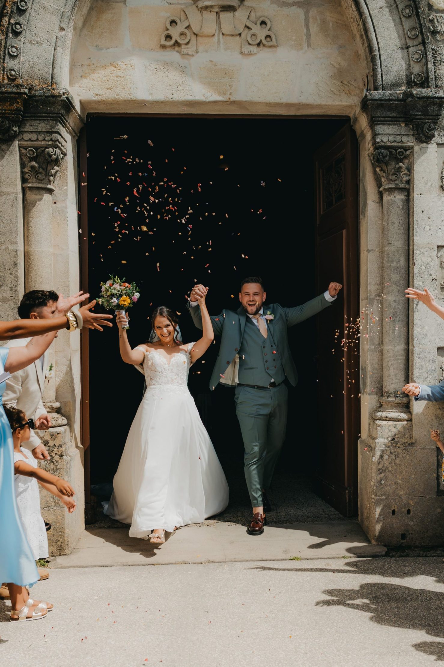 les mariés qui sortent de l'église en levant les bras