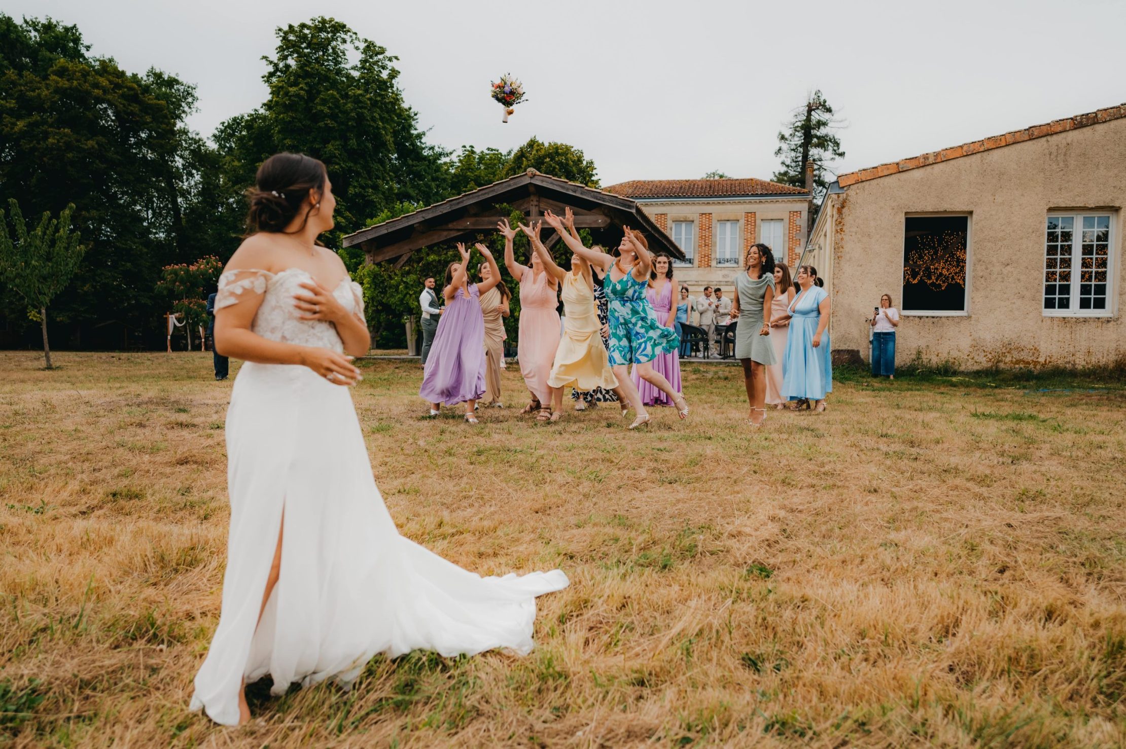 la mariée qui jette son bouquet et qui se retourne vers les filles