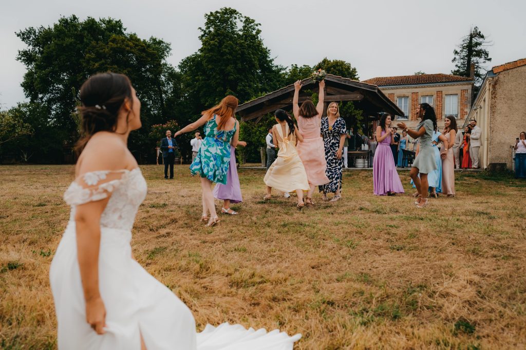 une invitée qui attrape le bouquet de la mariée