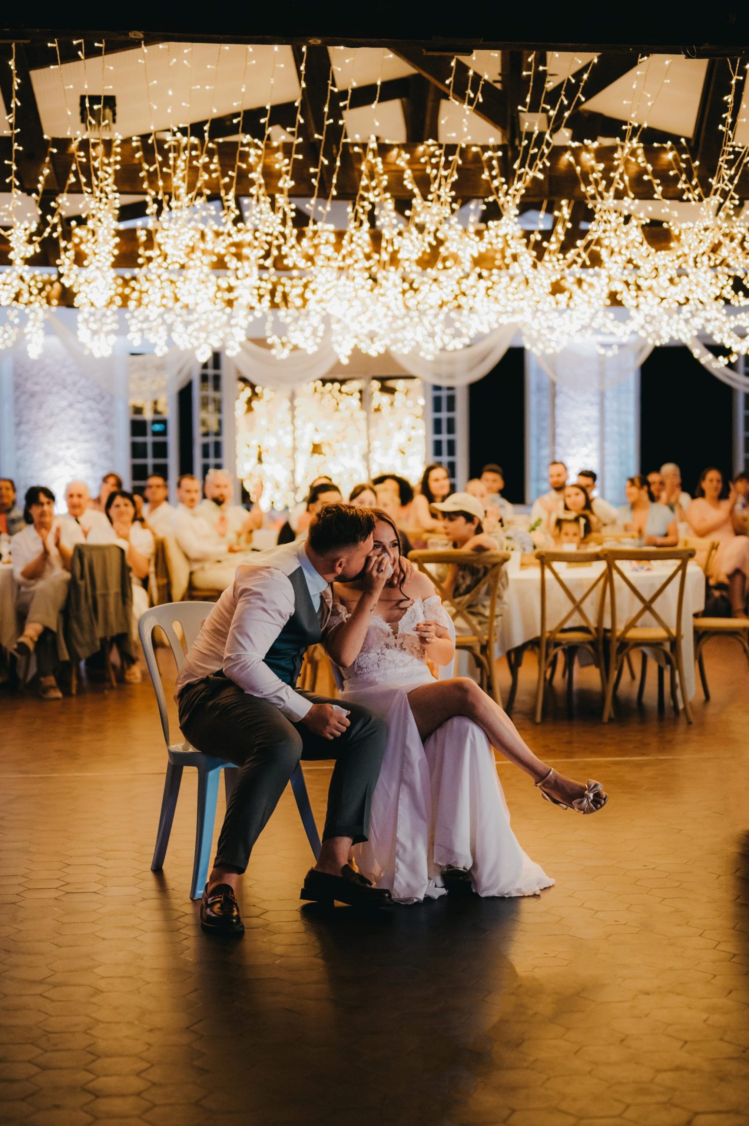 le marié qui dépose un bisou sur la joue de la mariée qui regarde un film surprise de ses souvenirs d'enfance