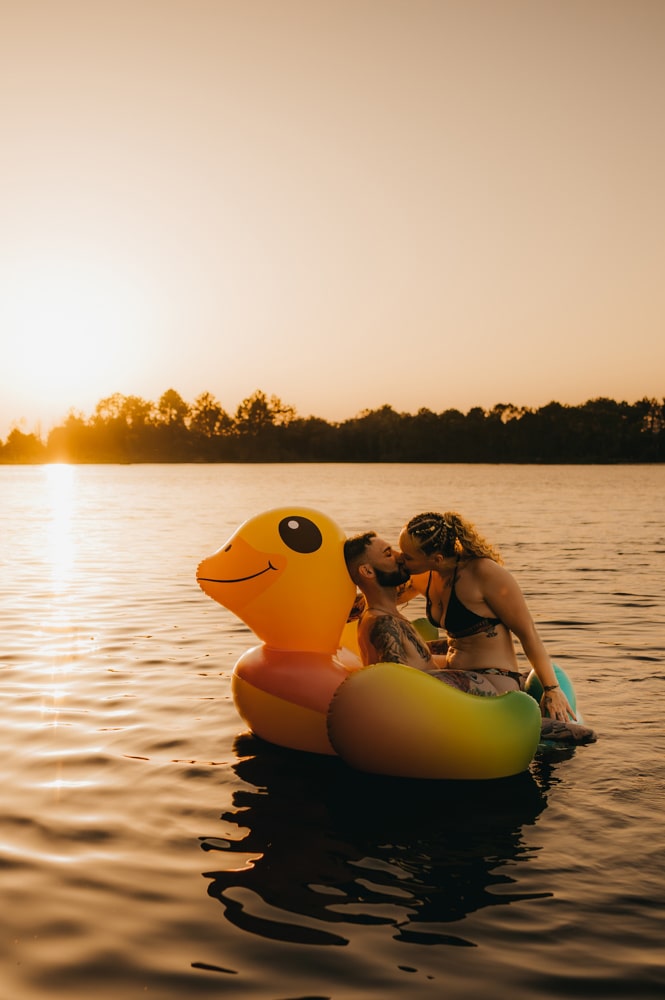 Couple romantique sur une bouée canard géante au lac d’Hostens qui se font un bisou sur la bouche