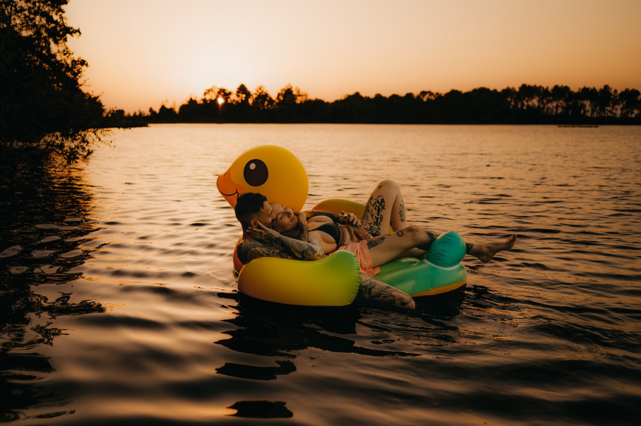 Couple flottant sur une grande bouée en forme de canard dans le lac d’Hostens