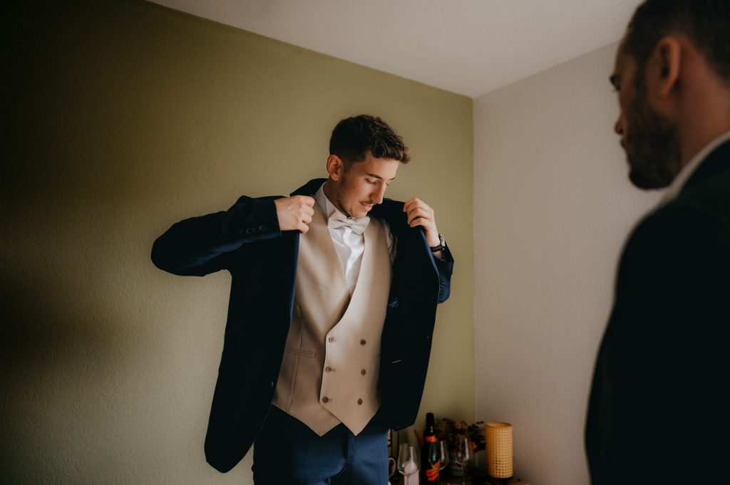 un jeune homme qui met sa veste de costume sur lui