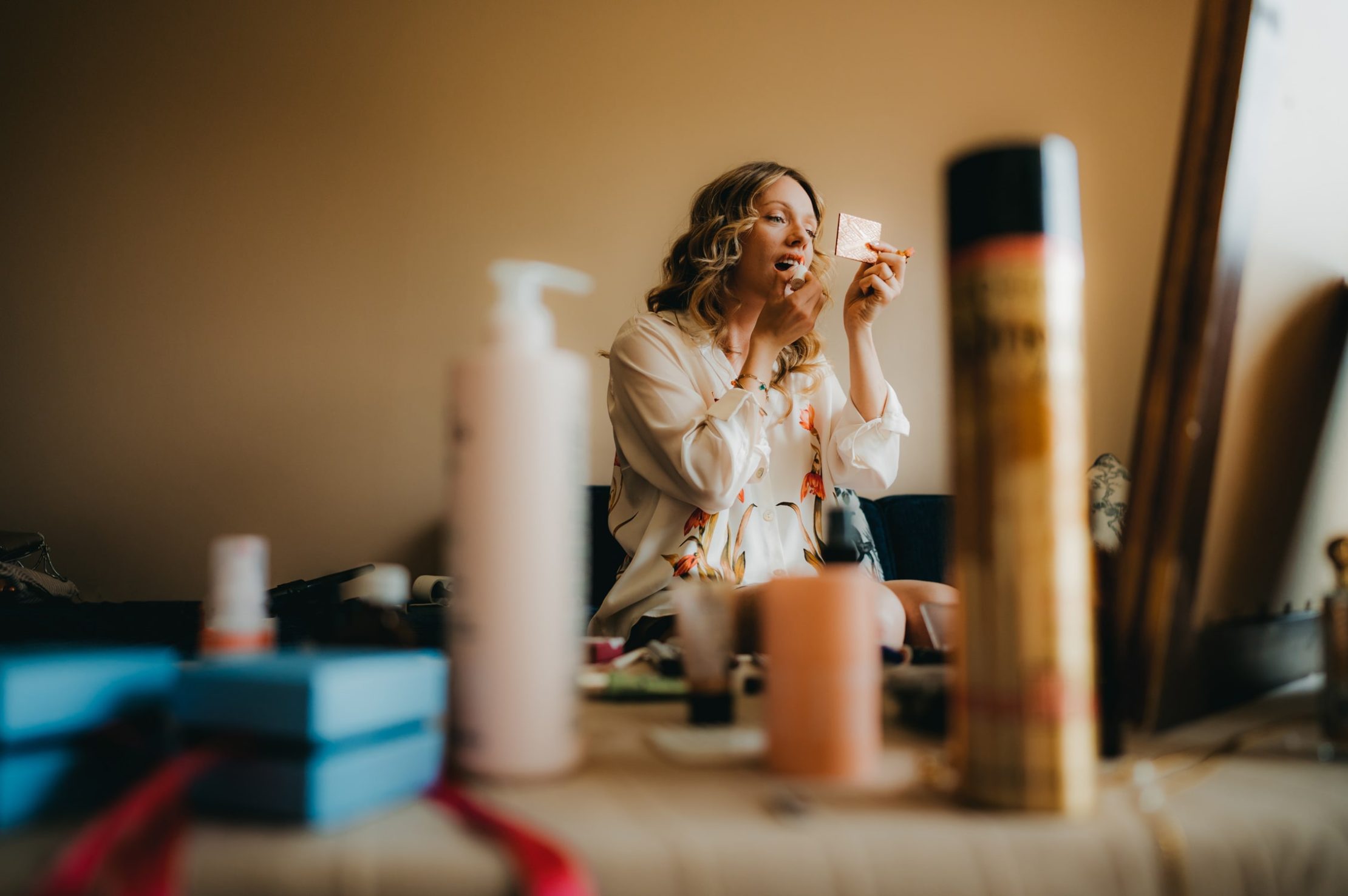 une jeune femme qui se maquille dans son salon
