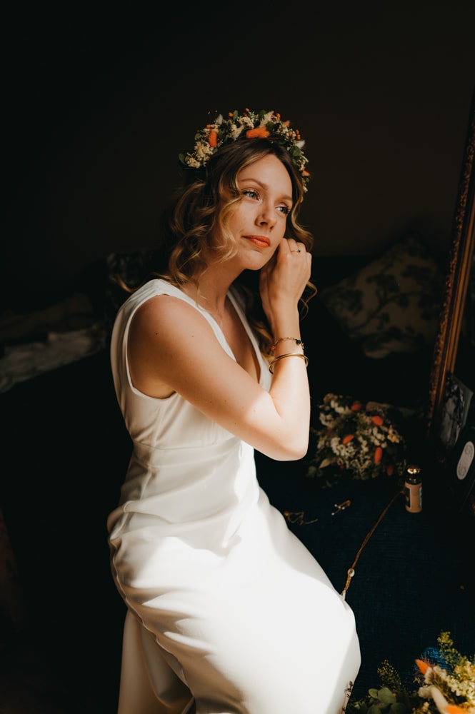 une jeune femme qui se met des boucles d'oreilles devant son miroir