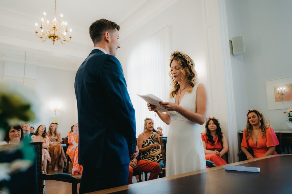 une mariée qui tient un discours dans ses mains, elle regarde son époux dans les yeux tout émue