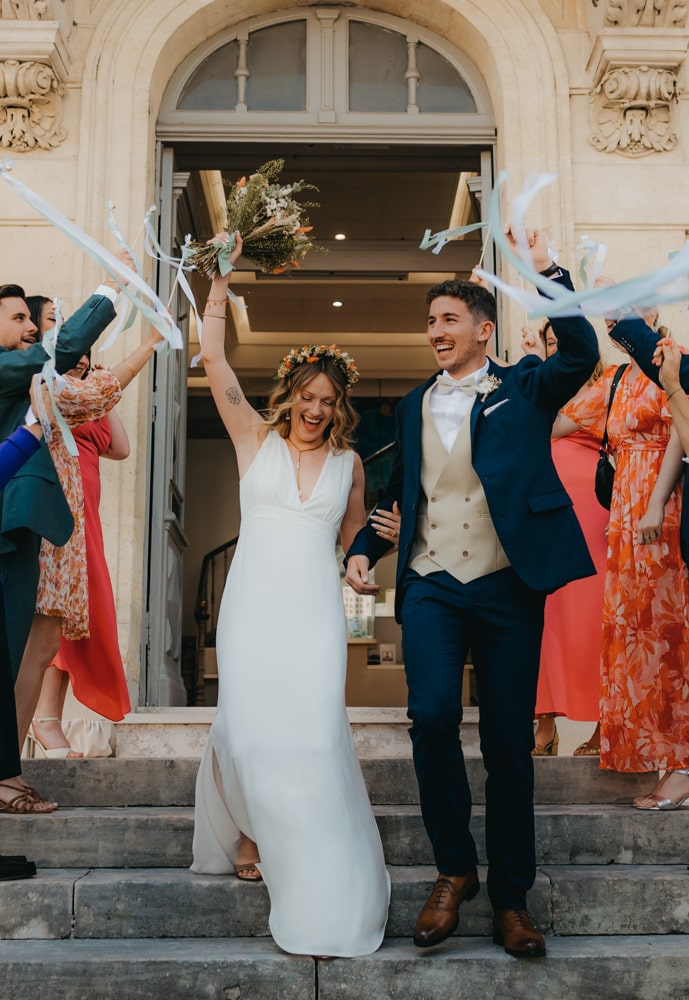 des mariés très souriants sortent de leur cérémonie civil sous les applaudissements de leurs invités