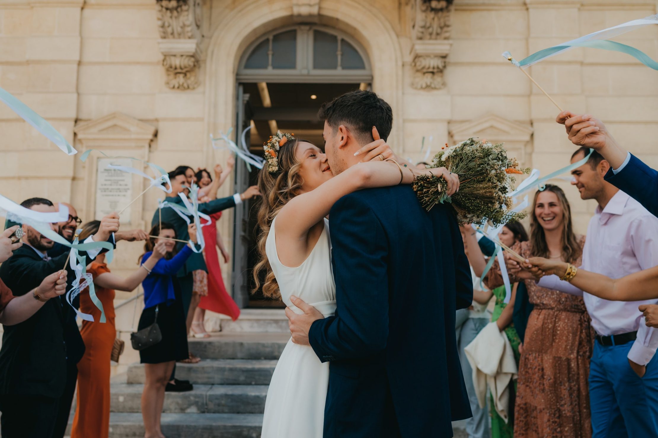 un jeune couple de mariés qui sortent tout juste de leur cérémonie civil et qui s'embrasse devant la mairie