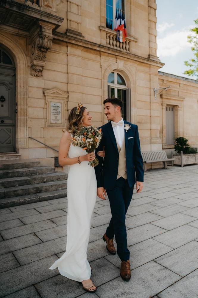 deux jeunes mariés qui se tiennent main dans la main et qui sorte de la mairie