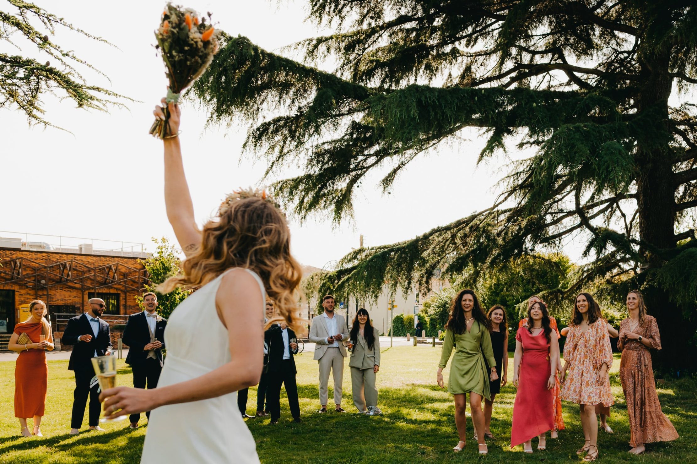 Mariée de dos lançant son bouquet dans une scène joyeuse
