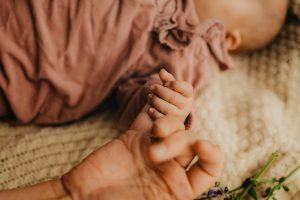 Le bébé tient la main de sa maman pendant sa séance photo naissance à Bordeaux, Gironde.