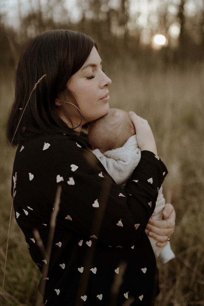 La photographe bordeaux & gironde tient son bébé dans ses bras et ferme les yeux. Beaucoup de douceur se dégage.