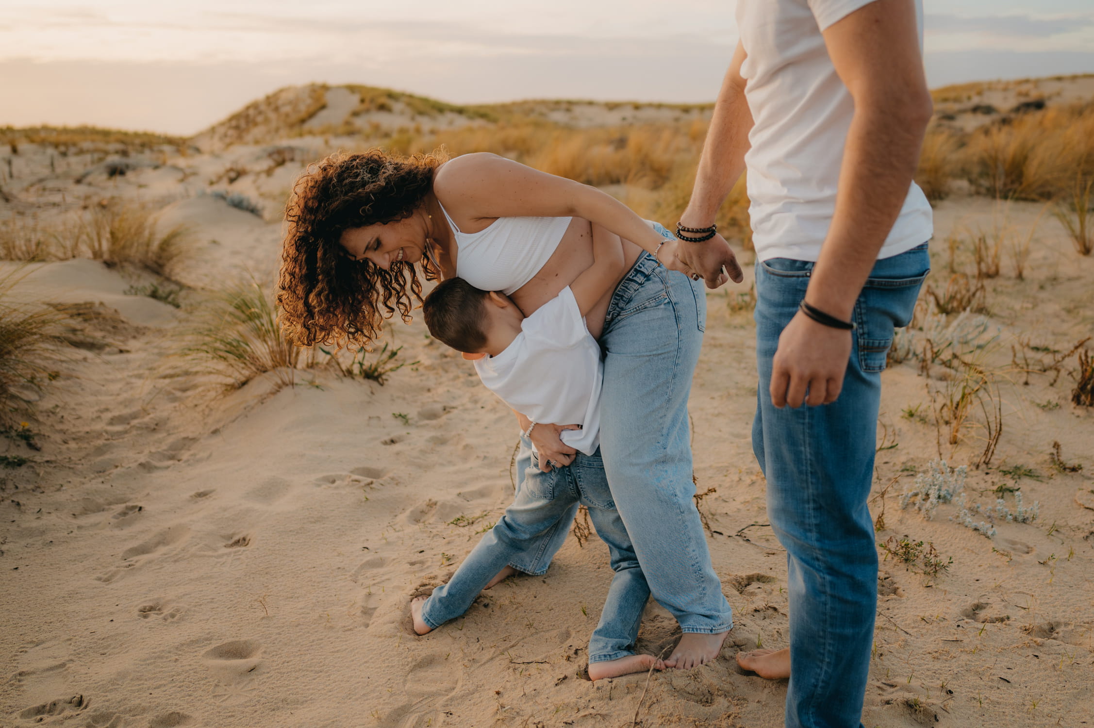 Moment complice entre parents et enfant lors d’un shooting grossesse en plein air