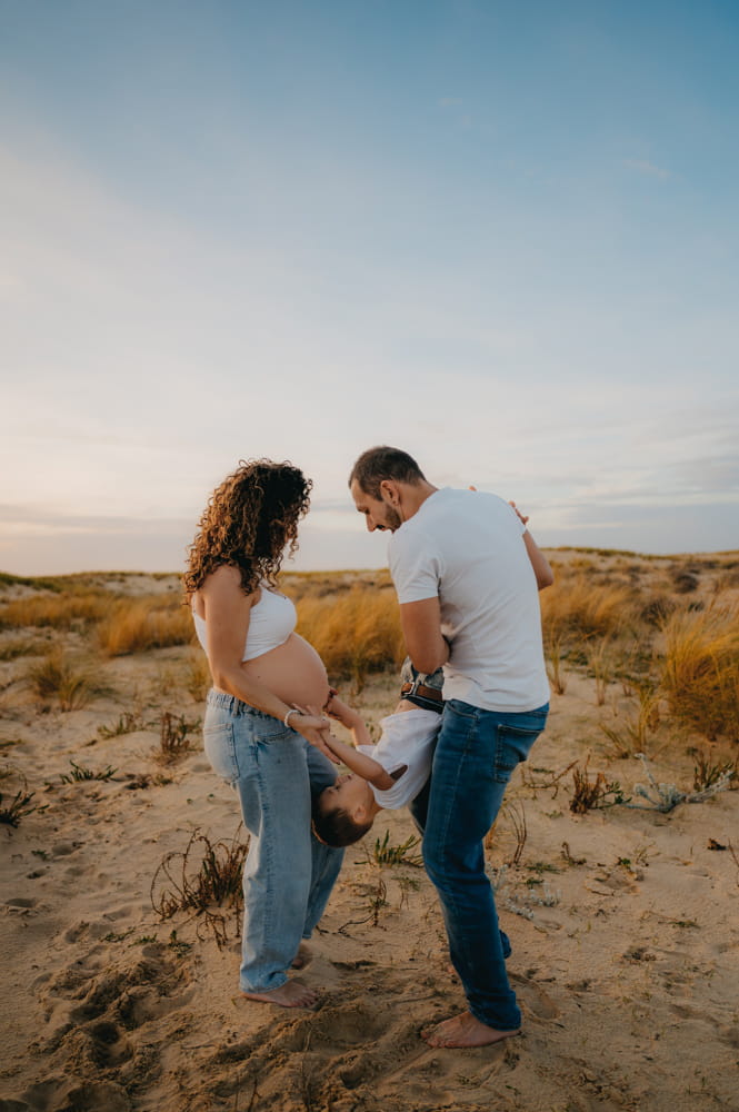 Parents et enfant riant ensemble sur la plage au coucher du soleil
