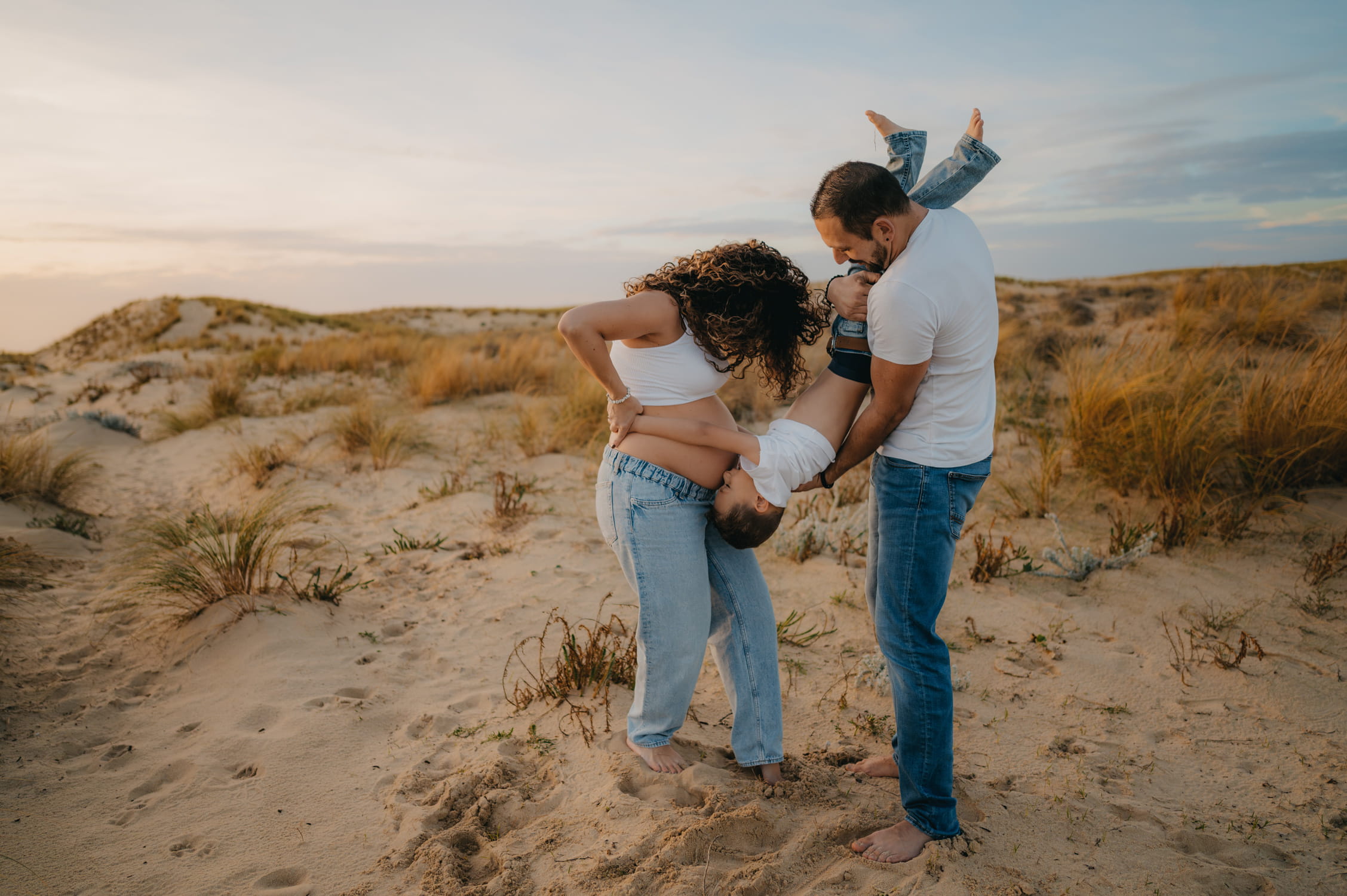 Famille s’amusant dans les dunes sous une lumière dorée