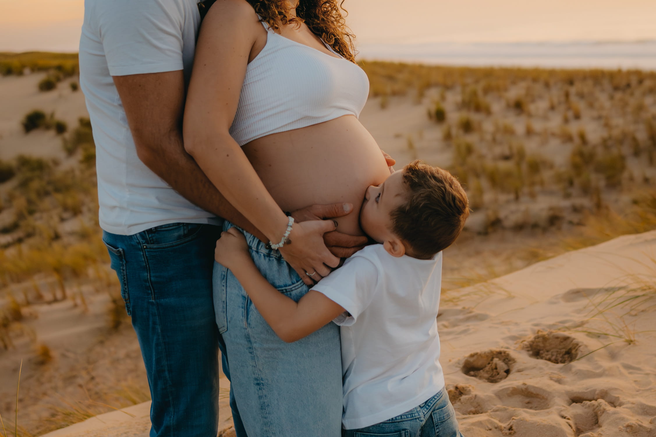 un enfant qui fait un bisou sur le ventre rond de sa maman