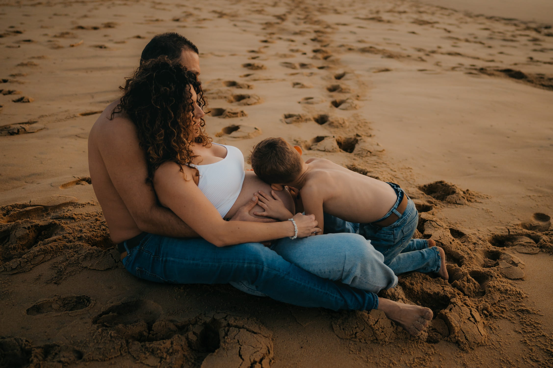 Papa et enfant embrassant le ventre arrondi de la maman
