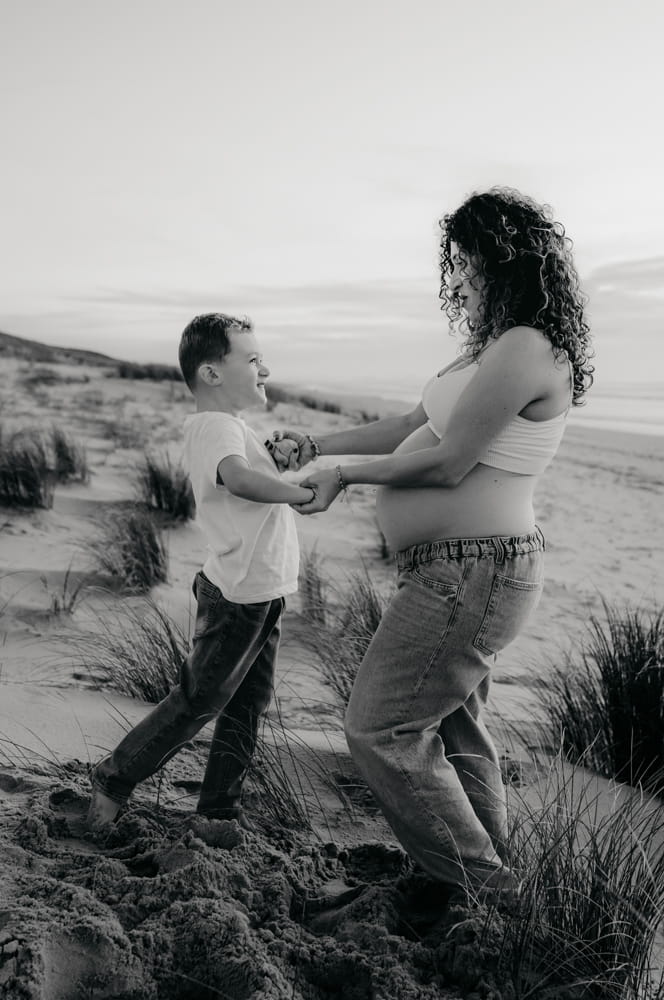 Maman enceinte jouant avec son enfant dans le sable