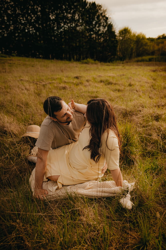 Couple enlacé dans les champs pendant une séance grossesse romantique près de Bordeaux